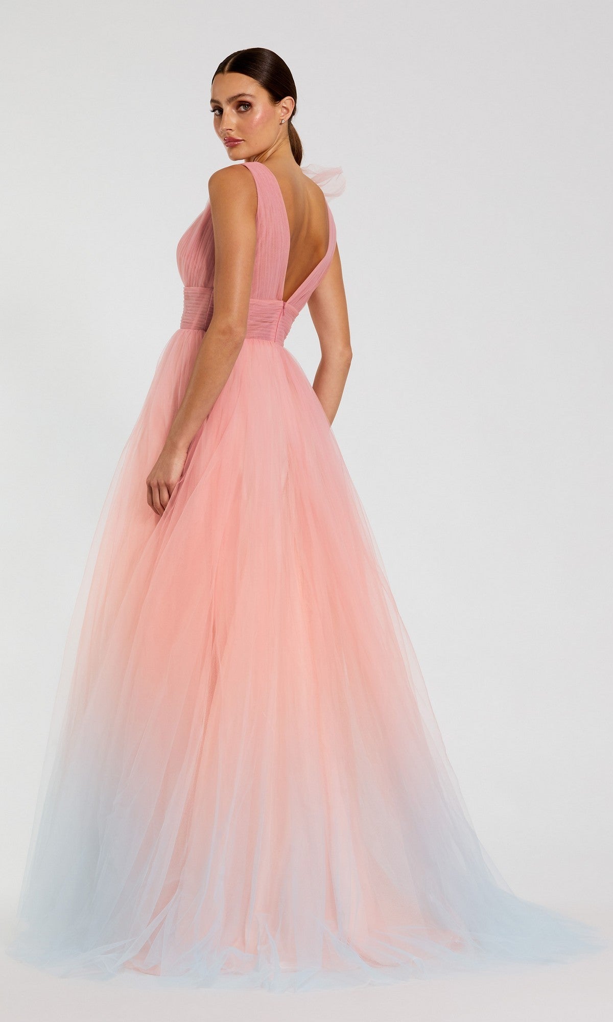 A woman wears the Long Formal Dress: Mac Duggal 37001, a sleeveless pink ombre ballgown with a gradient from pink at the top to light blue at the hem, standing against a plain background.